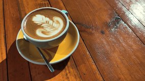 4k clip with speciality coffee cup with art latte depicting a flower 