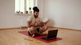 Bearded man talk on video call sit on yoga mat greets in namaste