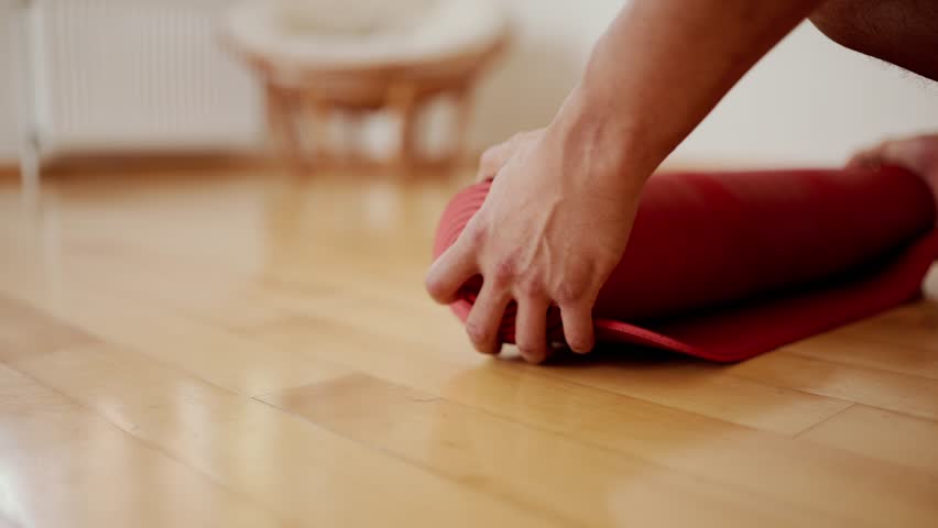 Male hands unfolding red yoga mat on wooden floor Royalty-Free Stock Footage #1101521803