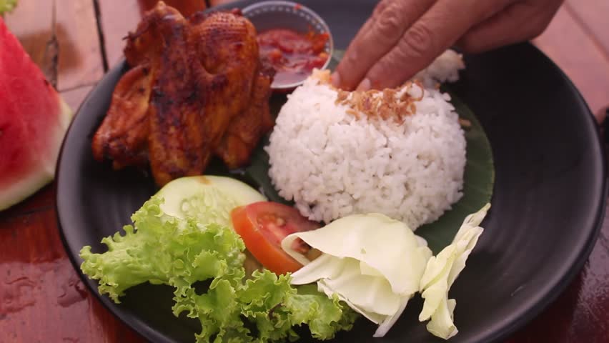 start eating a plate of rice with grilled chicken and chili sauce on the table