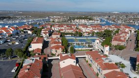 aerial footage of luxury homes with tennis courts and swimming pools surrounded by the blue waters of Huntington Harbour with boats and yachts docked in Huntington Beach California USA