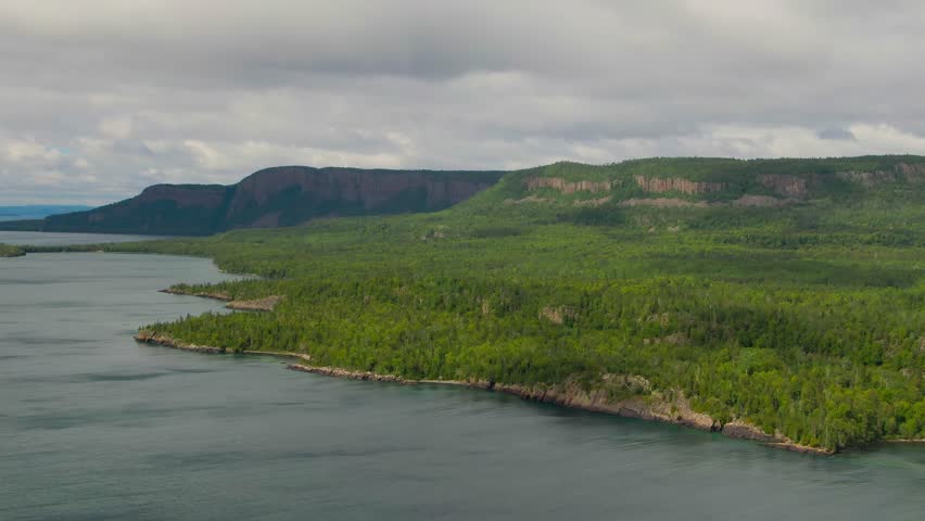 Aerial view of blue water Lake Superior with green Canadian coastline Sleeping Giant Silver Islet Evergreen Trees Mountain Cliffs in background
