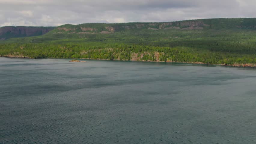 Aerial view of blue water Lake Superior with green Canadian coastline Sleeping Giant Silver Islet Evergreen Trees Mountain Cliffs in background