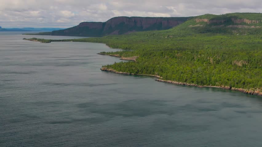Aerial view of blue water Lake Superior with green Canadian coastline Sleeping Giant Silver Islet Evergreen Trees Mountain Cliffs in background