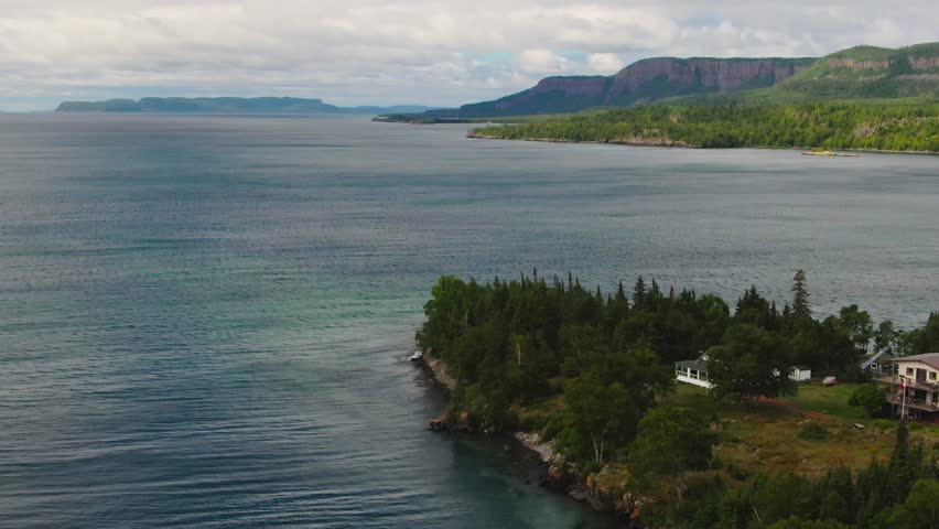 Aerial view of blue water Lake Superior with green Canadian coastline Sleeping Giant Silver Islet Evergreen Trees Mountain Cliffs in background