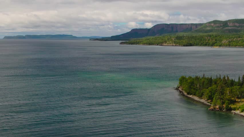 Aerial view of blue water Lake Superior with green Canadian coastline Sleeping Giant Silver Islet Evergreen Trees Mountain Cliffs in background
