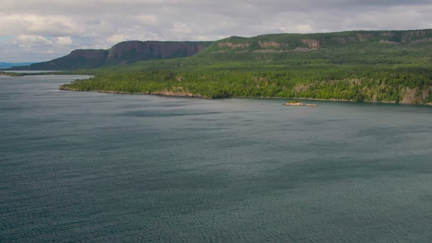 Aerial view of blue water Lake Superior with green Canadian coastline Sleeping Giant Silver Islet Evergreen Trees Mountain Cliffs in background