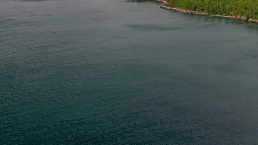 Aerial view of blue water Lake Superior with green Canadian coastline Sleeping Giant Silver Islet Evergreen Trees Mountain Cliffs in background
