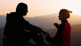 Silhouette of mother with daughter on top of mountain. They are resting, drinking tea, talking and laughing. Mother's day concept, 4k - Powered by Shutterstock - Get 15% off with code: PIKWIZARD15