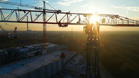 Drone point of view moving up around crane tower in construction site sunrise. Close up view of the crane tower lifting material in building site. Industry construction concept footage. - Powered by Shutterstock - Get 15% off with code: PIKWIZARD15