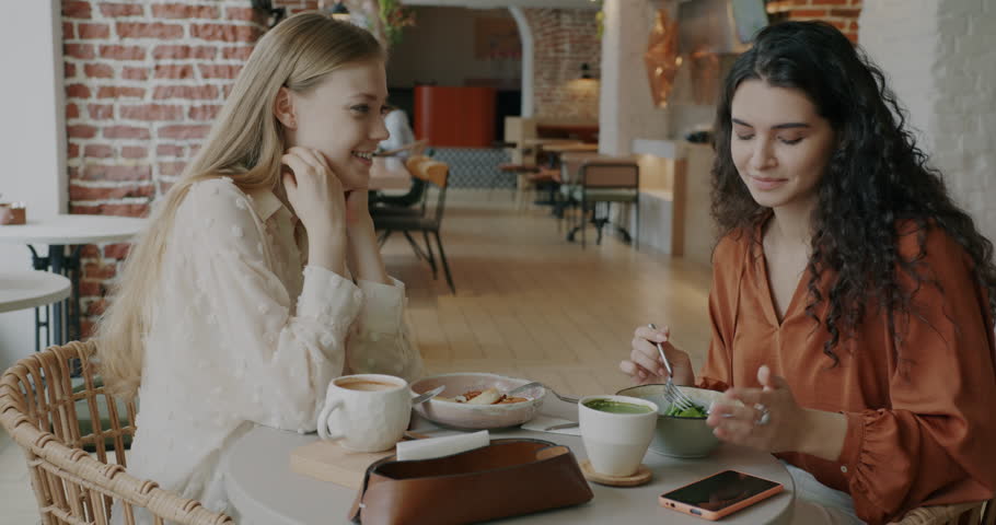 Young woman showing engagement ring sharing good news with friend during lunch break in cafe. Friendship and relationship concept. | Shutterstock HD Video #1101529715