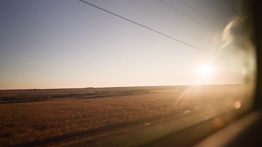 Bullet train rides on the railway track during a beautiful sunset. Journey and trip on train. Interior view at train's empty window. Royalty-Free Stock Footage #1101529837