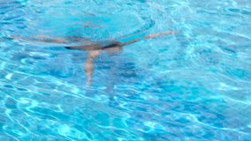Boy swimming in a pool. Little boy in swimming goggles swimming under water in a swimming pool.