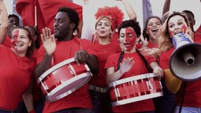 Crazy football fans celebrating in the crowd while watching the game at sport stadium - Soccer supporters screaming for their red team during world champion event - Powered by Shutterstock - Get 15% off with code: PIKWIZARD15