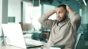 Surprised young businessman sees shocking information on laptop screen while sitting at workplace at desk in modern office. Upset man feeling stressed reading bad news He holds his head with his hands - Powered by Shutterstock - Get 15% off with code: PIKWIZARD15