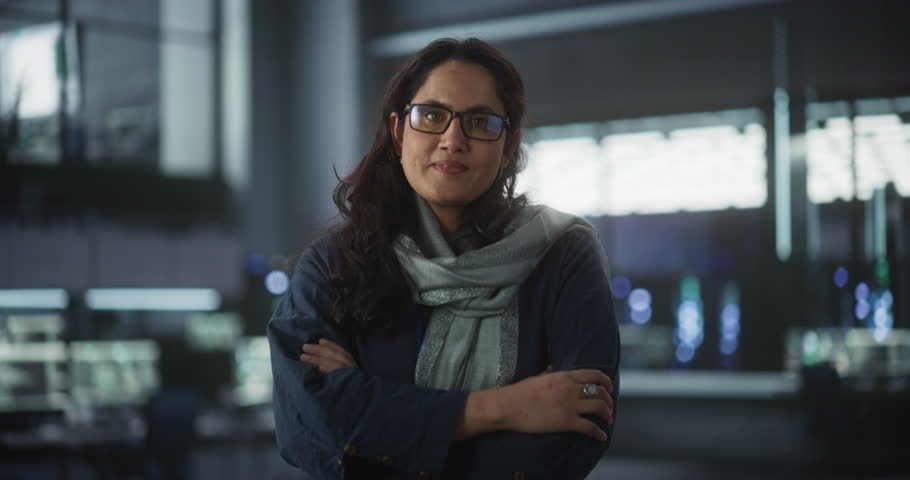 Portrait of Beautiful Smiling IT Specialist Posing for Camera in Data Science Laboratory. Young Indian Female Looking at Camera. Succesful Woman Working in Big Server Farm Cloud Computing Company