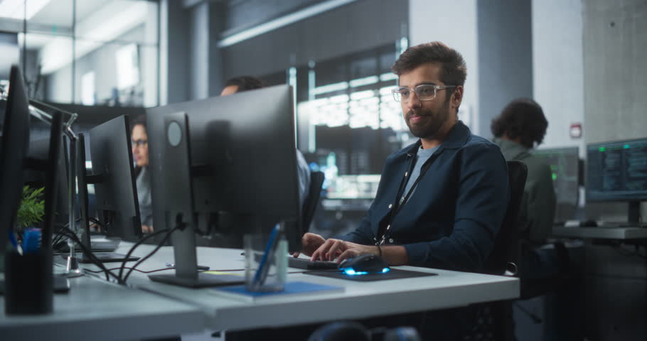 Portrait of a Thoughtful Engineer Working on Desktop Computer in a Technological Office Environment. Research and Development Department Writing Software Code for an Advanced Neural Network Project Royalty-Free Stock Footage #1101540031