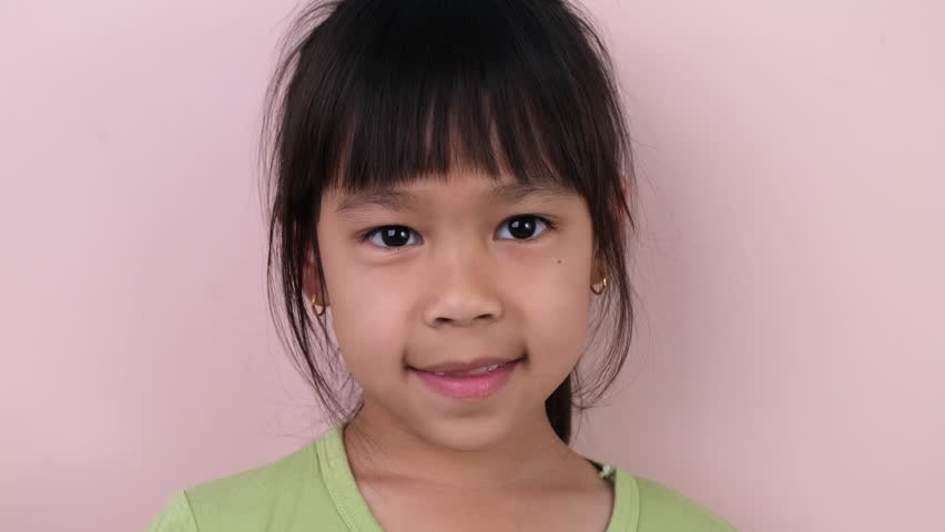 Cute little girl in headphones listen to music. Wireless headset device accessory. Child enjoying music in earphones on pastel pink background in studio.