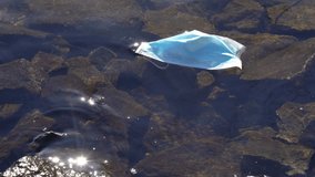 Used face mask from Covid 19 pandemic floating in Norway fjord. Close up. - Powered by Shutterstock - Get 15% off with code: PIKWIZARD15