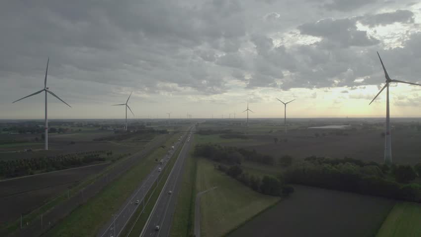 Panoramic aerial view on a windmill farm along a highway and railroad from drone. Cinematic aerial view of large wind turbines producing clean sustainable energy, clean energy future. Windmill farm in | Shutterstock HD Video #1101545229