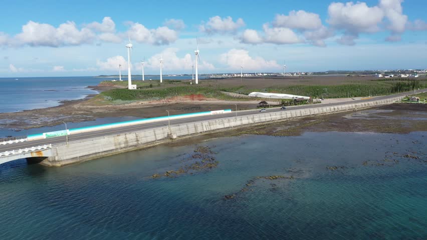 Aerial view of giant wind turbines standing in the green field by the beach in a seaside park along the beautiful coastline on a sunny summer day, in Zhongtun, Baisha Township, Penghu County, Taiwan | Shutterstock HD Video #1101546239