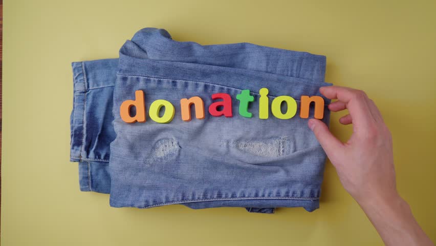 Jeans with the inscription donation, concept of helping people in need. Give to charity, yellow background | Shutterstock HD Video #1101546321
