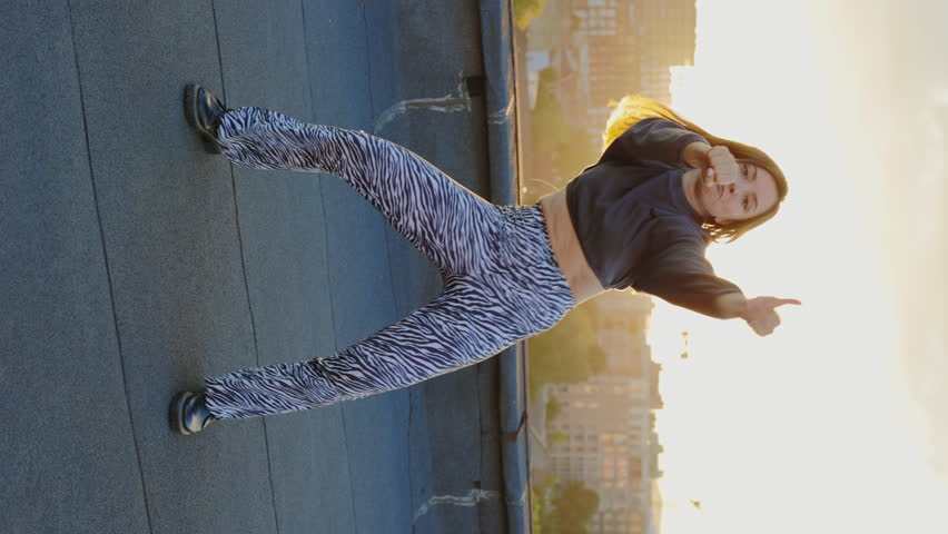 Vertical video. Attractive hip-hop woman emotionally dancing on the roof floor while the sunset looking at camera performing amazing gestures and movements outside. Street dance | Shutterstock HD Video #1101547163