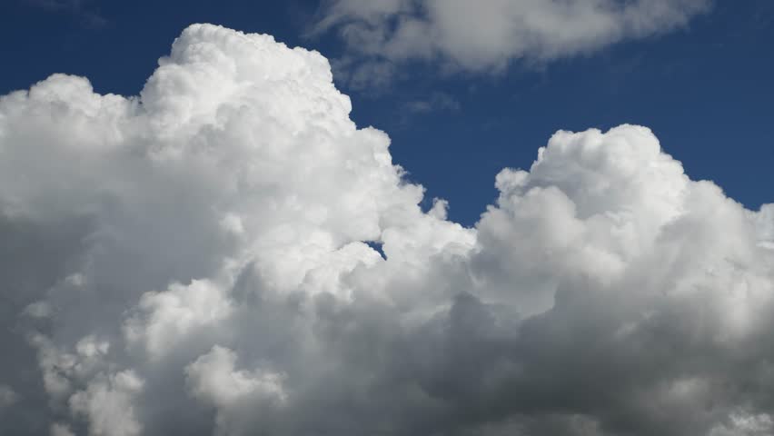 Low angle view of time lapse of beautiful white storm clouds and vibrant sunlight, blue sky