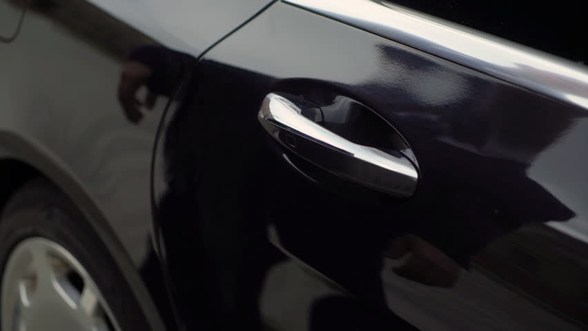 A man in a suit opens the back door of a premium car. Luxurious black vehicle. The driver takes the door handle with his hand. VIP taxi transport service. Royalty-Free Stock Footage #1101553541