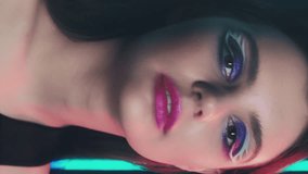 Vertical video. Retro makeup. 90s beauty. 2000s nostalgia. Cheerful teen girl fashion model face with blue color eyeshadow pink lips artistic look posing in neon light on dark. - Powered by Shutterstock - Get 15% off with code: PIKWIZARD15