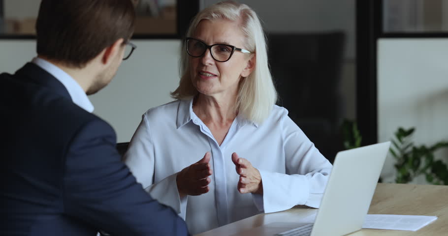 Consultation, mentorship, formal meeting of manager and client. Mature businesslady lead talk to male business partner, colleagues share strategy, planning future cooperation, take part in negotiation Royalty-Free Stock Footage #1101557175