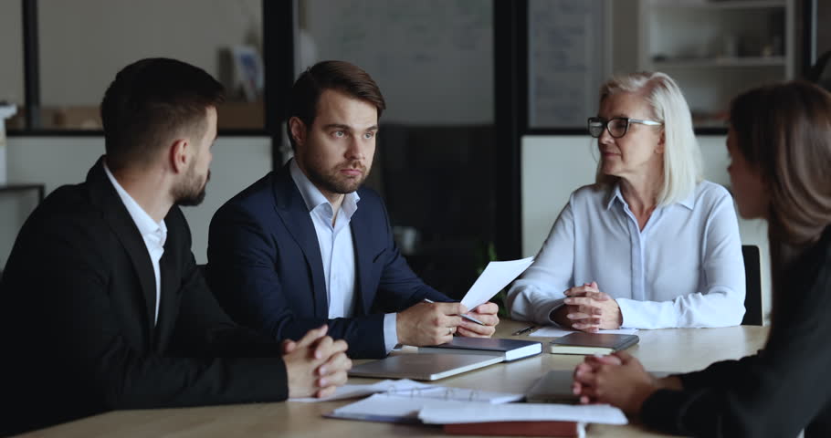 Young and mature staff listening team leader, company boss make speech, reporting about sales results, strategy, corporate goals at group meeting in conference room. Negotiations, training, business Royalty-Free Stock Footage #1101557179