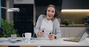 Young teenage girl playing video game in moderm kitchen apartment enjoying indoor activity. Online entertainment and leisure activity concept.