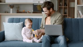 Gig economy and parenthood. Young positive man independent contractor playing with his baby daughter and typing on laptop, working remotely from home, tracking shot, slow motion, free space