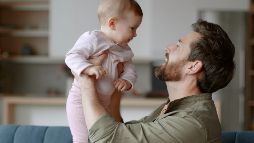 Unconditional father love. Close up portrait of happy loving father holding his lovely adorable baby daughter on hands, hugging and rubbing noses, tracking shot, slow motion, empty space Royalty-Free Stock Footage #1101571173