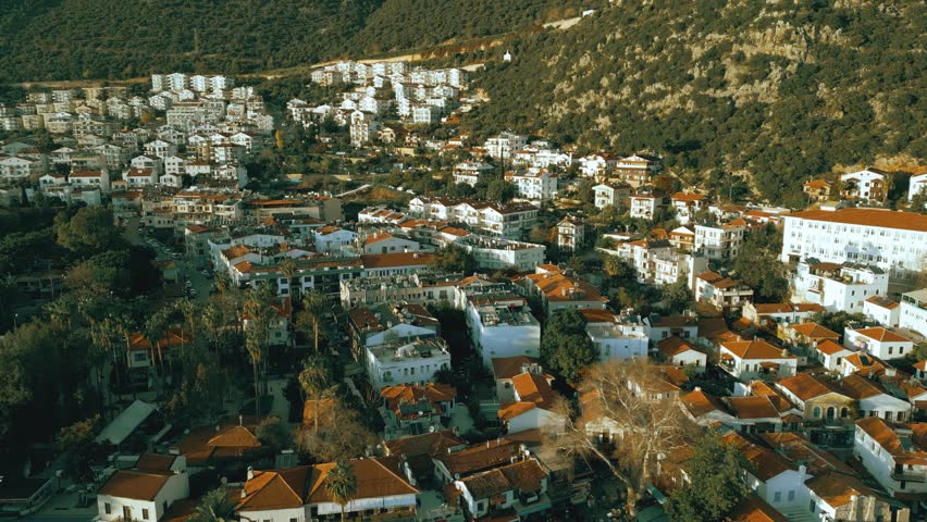 Aerial view of white tiled houses located on the mountain in Kas at sunset, Turkey