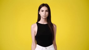 4k video of cute girl waving hello on yellow background.