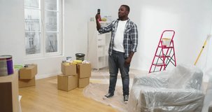 Portrait of successful professional African American designer recording video using smartphone taking vlog showing people how to renovate apartment. Handsome African male blogger renewing flat.