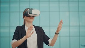 Woman Engineer Wearing Virtual Reality Headset Works and Gestures in Augmented Reality While Standing Near a Building With Blue Windows. VR Transformation. - Powered by Shutterstock - Get 15% off with code: PIKWIZARD15