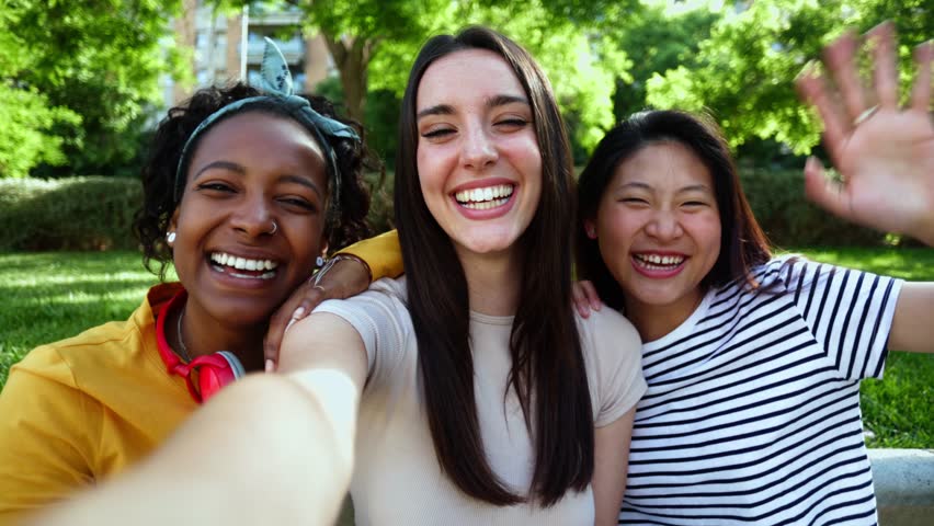 Smiling diverse young female friends having video call using mobile phone app. Multiracial three women having fun together talking on virtual meeting by cellphone during summer holidays | Shutterstock HD Video #1101595715