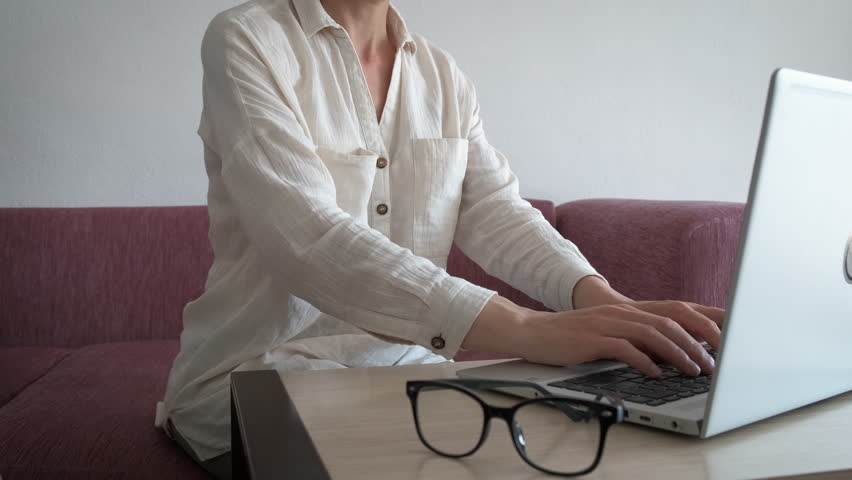 Freelancer massaging painful wrist. A view of woman massaging her wrist after computer work in her home office. A concept of freelancer proffesional trauma.