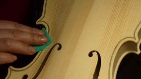 woman violin maker artisan using sandpaper on new violin to smooth table surface 4k footage