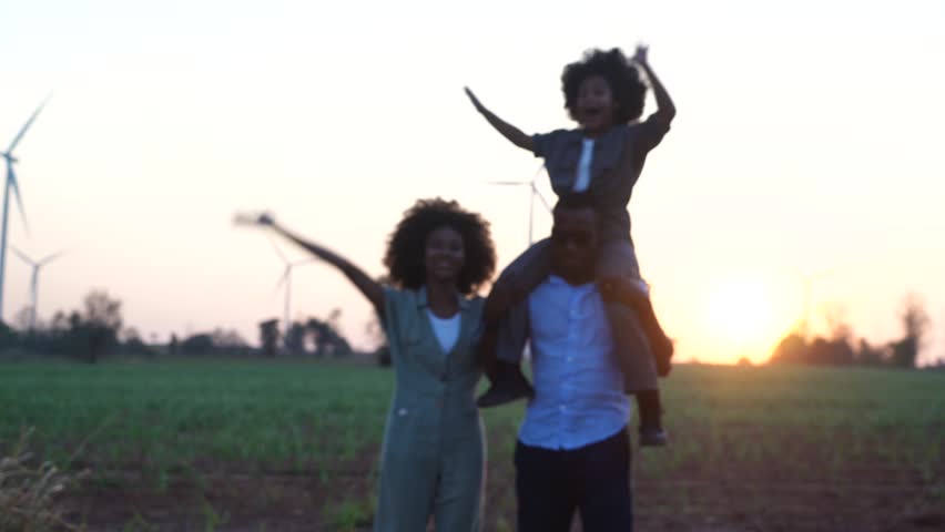Family Responsibility, Corporate Social Responsibility and sustainable energy concept.African american black family daughter holding a plane sitting on father's shoulder watching a field of turbines  | Shutterstock HD Video #1101607467