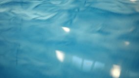 Close-up blue water splashing in sunshine as unrecognizable swimmer passing. Waves in sunlight indoors in swimming pool - Powered by Shutterstock - Get 15% off with code: PIKWIZARD15