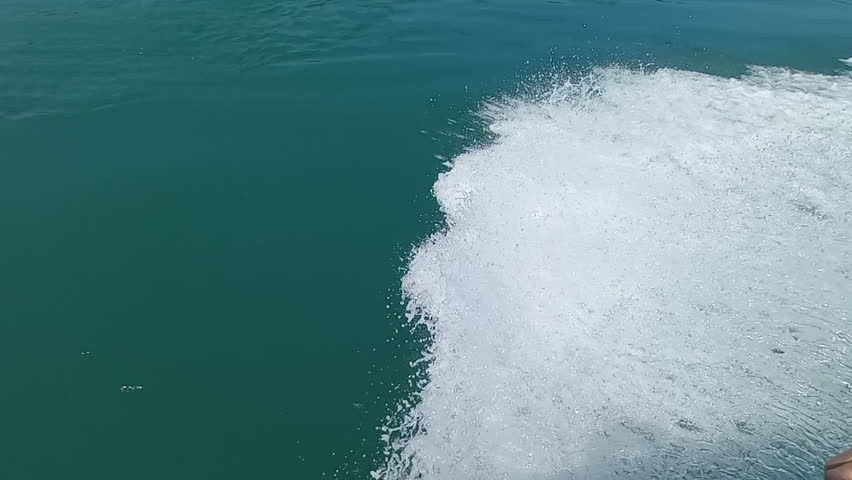 Mass of water displaced from a small boat at speed, in calm and blue sea, beautiful effect that water makes | Shutterstock HD Video #1101611121