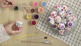 Easter Eggs. Female hands painting with paints and brush on an Easter eggs, vertical video