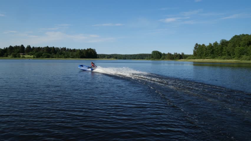 A motorboat rushes through the waves on a lake against the background of a forest | Shutterstock HD Video #1101613099