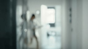 Blurred video of medical staff walking across the hospital corridor. Shot with RED helium camera in 8K.