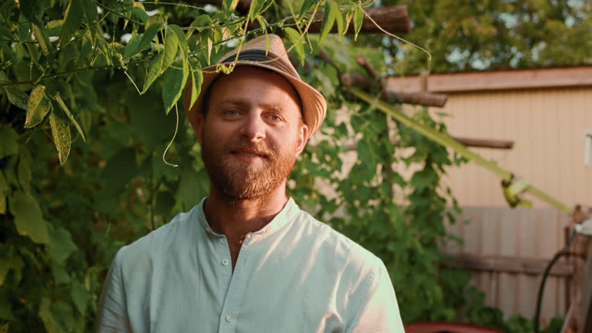 Organic gardening. Portrait of bearded smiling caucasian farmer posing at garden. Slow motion. The concept of harvesting and farming. | Shutterstock HD Video #1101615467