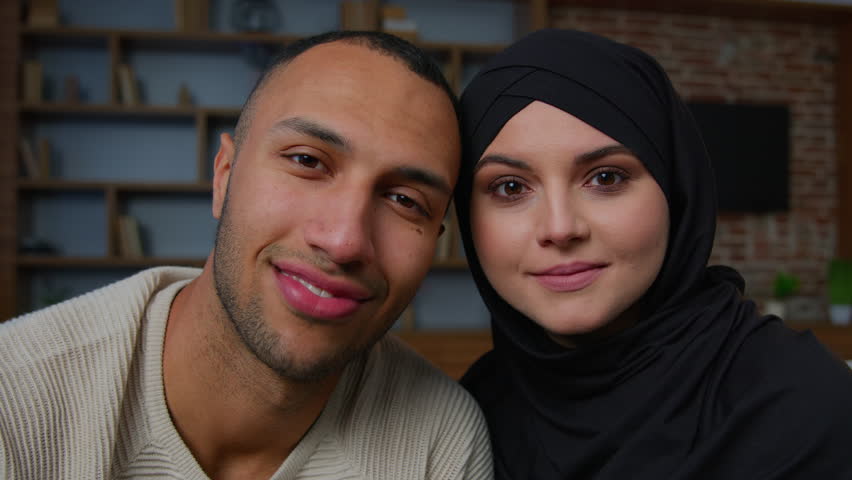 Multiracial ethnic couple african american man smiling muslim woman in hijab looking through joined fingers heart shape united hands frame Valentines Day romantic loving wife husband relationship love Royalty-Free Stock Footage #1101617845